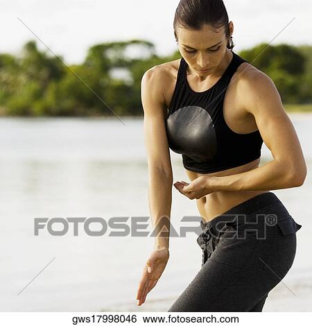 Stock Photograph - Young woman practicing martial arts on the beach. Fotosearch