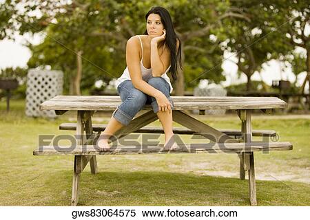 Young woman sitting on a bench with her hand under her chin View Large Photo Image Stock Photography - Young woman sitting on a bench with her hand under her chin. Fotosearch