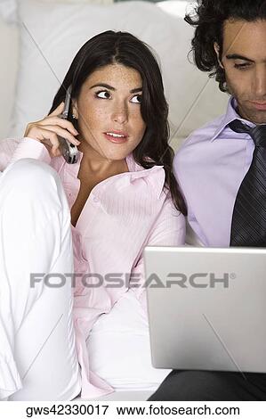 Young woman talking on the telephone with a mid adult man using a laptop View Large Photo Image Stock Photo - Young woman talking on the telephone with a mid adult man using a laptop. Fotosearch