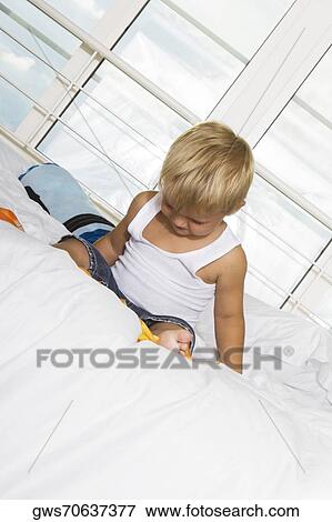 Boy sitting on the bed View Large Photo Image Stock Photo - Boy sitting on the bed. Fotosearch
