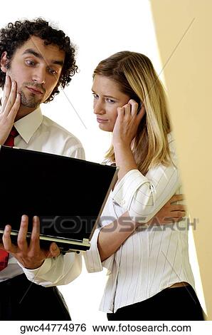 Stock Photograph - Businessman and a businesswoman looking at a laptop. Fotosearch