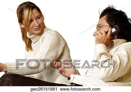 Businessman talking on a mobile phone with a businesswoman sitting beside her View Large Photo Image Stock Image - Businessman talking on a mobile phone with a businesswoman sitting beside her. Fotosearch