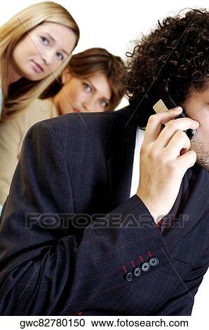 Businessman talking on a mobile phone with his two secretaries standing behind him View Large Photo Image Stock Image - Businessman talking on a mobile phone with his two secretaries standing behind him. Fotosearch