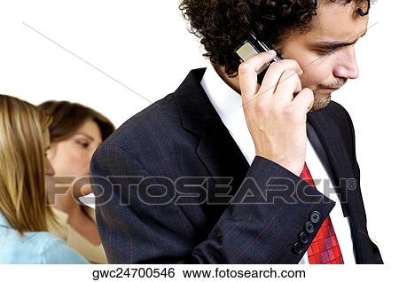 Stock Photograph - Businessman talking on a mobile phone with his two secretaries standing behind him. Fotosearch