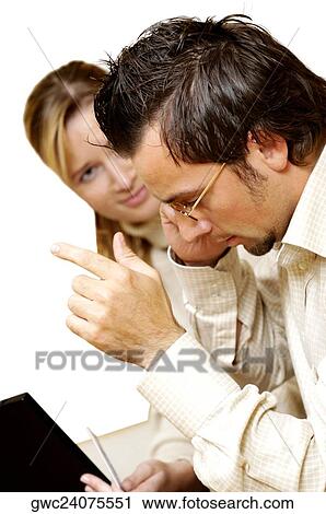 Stock Image - Businesswoman holding a credit card with a businessman talking on a mobile phone beside her. Fotosearch