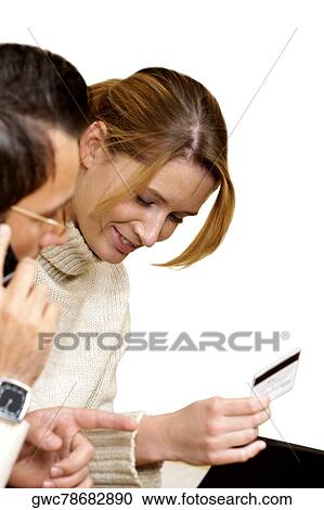 Businesswoman holding a credit card with a businessman talking on a mobile phone beside her View Large Photo Image Stock Image - Businesswoman holding a credit card with a businessman talking on a mobile phone beside her. Fotosearch