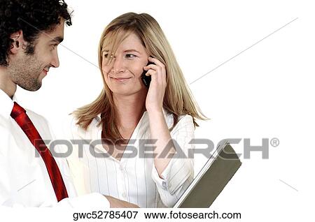 Businesswoman talking on a mobile phone looking at a businessman View Large Photo Image Stock Photo - Businesswoman talking on a mobile phone looking at a businessman. Fotosearch