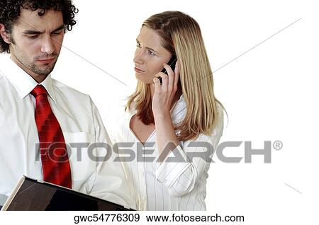 Stock Photo - Businesswoman talking on a mobile phone looking at a businessman. Fotosearch