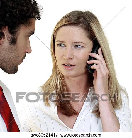 Businesswoman talking on a mobile phone looking at a businessman View Large Photo Image Stock Photo - Businesswoman talking on a mobile phone looking at a businessman. Fotosearch
