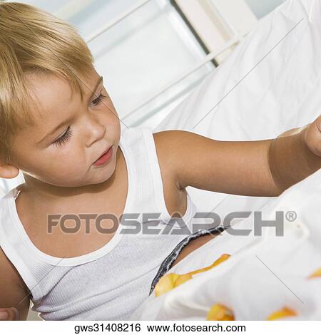 Close-up of a boy sitting on the bed playing with rose petals View Large Photo Image Stock Photograph - Close-up of a boy sitting on the bed playing with rose petals. Fotosearch