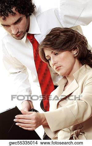 Picture - Close-up of a businessman and a businesswoman looking at a laptop. Fotosearch