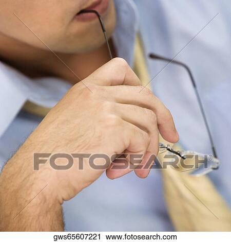 Close-up of a businessman holding a pair of eyeglasses View Large Photo Image Stock Image - Close-up of a businessman holding a pair of eyeglasses. Fotosearch