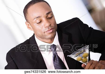 Close-up of a businessman holding a martini glass View Large Photo Image Stock Photograph - Close-up of a businessman holding a martini glass. Fotosearch