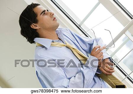 Close-up of a businessman holding a pair of eyeglasses View Large Photo Image Stock Photography - Close-up of a businessman holding a pair of eyeglasses. Fotosearch