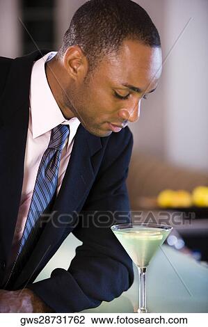 Stock Image - Close-up of a businessman looking at a glass of martini. Fotosearch