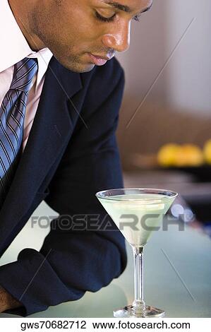 Close-up of a businessman looking at a glass of martini View Large Photo Image Stock Image - Close-up of a businessman looking at a glass of martini. Fotosearch