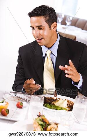 Close-up of a businessman sitting at a table and eating View Large Photo Image Stock Image - Close-up of a businessman sitting at a table and eating. Fotosearch
