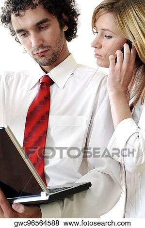 Stock Photo - Close-up of a businessman using a laptop with a businesswoman talking on a mobile phone. Fotosearch