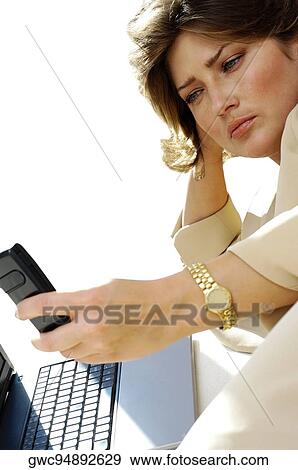 Stock Photo - Close-up of a businesswoman using a mobile phone in front of a laptop. Fotosearch