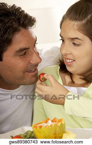 Close-up of a daughter feeding her father a strawberry View Large Photo Image Stock Image - Close-up of a daughter feeding her father a strawberry. Fotosearch