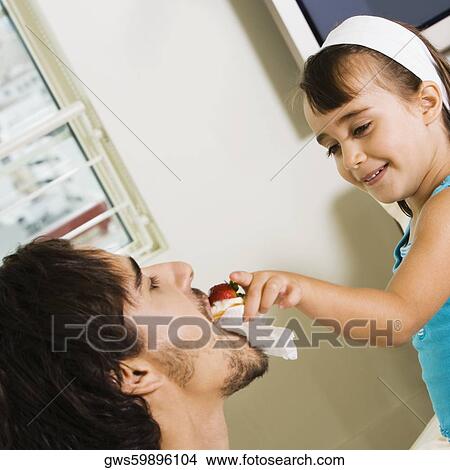 Close-up of a girl feeding her father View Large Photo Image Picture - Close-up of a girl feeding her father. Fotosearch