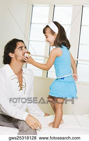 Close-up of a girl feeding her father View Large Photo Image Stock Photo - Close-up of a girl feeding her father. Fotosearch