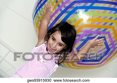 Stock Image - Close-up of a girl holding a large inflatable ball over her head. Fotosearch