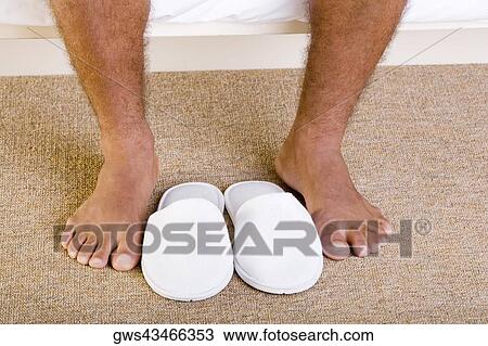 Close-up of a man's feet near a pair of slippers View Large Photo Image Stock Image - Close-up of a man's feet near a pair of slippers. Fotosearch