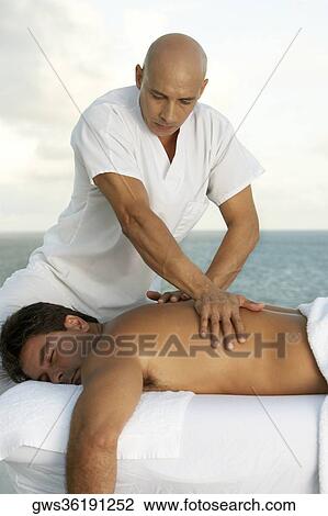 Close-up of a massage therapist giving a young man a back massage View Large Photo Image Stock Image - Close-up of a massage therapist giving a young man a back massage. Fotosearch