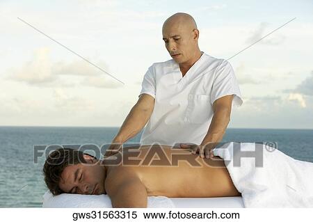 Close-up of a massage therapist giving a young man a back massage View Large Photo Image Stock Photography - Close-up of a massage therapist giving a young man a back massage. Fotosearch
