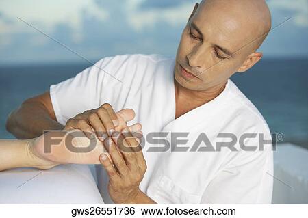 Stock Photograph - Close-up of a massage therapist massaging a woman's leg. Fotosearch