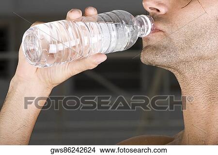 Close-up of a mid adult man drinking water from a bottle View Large Photo Image Picture - Close-up of a mid adult man drinking water from a bottle. Fotosearch