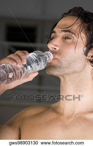 Close-up of a mid adult man drinking water from a bottle View Large Photo Image Stock Image - Close-up of a mid adult man drinking water from a bottle. Fotosearch