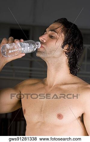 Stock Photo - Close-up of a mid adult man drinking water from a bottle. Fotosearch