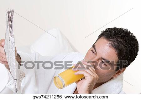 Close-up of a mid adult man holding a newspaper and drinking juice View Large Photo Image Stock Photograph - Close-up of a mid adult man holding a newspaper and drinking juice. Fotosearch