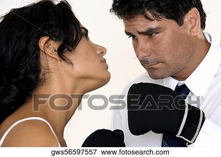 Close-up of a mid adult man wearing boxing glove staring at a young woman View Large Photo Image Stock Photo - Close-up of a mid adult man wearing boxing glove staring at a young woman. Fotosearch