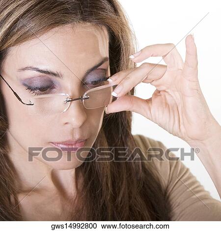 Stock Image - Close-up of a mid adult woman adjusting her eyeglasses. Fotosearch