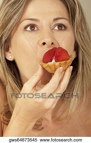 Close-up of a mid adult woman eating a strawberry tart View Large Photo Image Stock Photography - Close-up of a mid adult woman eating a strawberry tart. Fotosearch