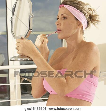 Close-up of a mid adult woman holding a mirror applying lipstick View Large Photo Image Stock Image - Close-up of a mid adult woman holding a mirror applying lipstick. Fotosearch