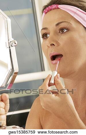 Close-up of a mid adult woman holding a mirror applying lipstick View Large Photo Image Stock Photo - Close-up of a mid adult woman holding a mirror applying lipstick. Fotosearch