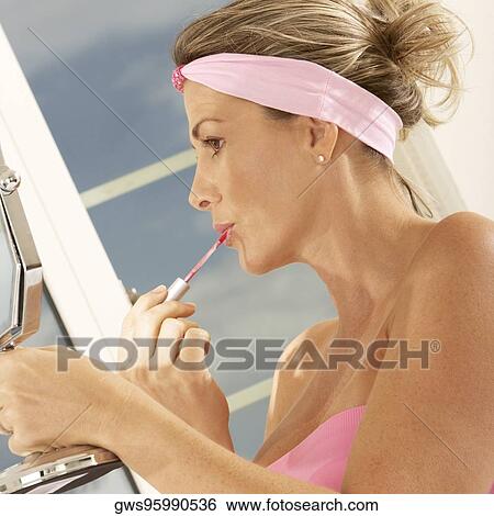 Close-up of a mid adult woman holding a mirror applying lipstick View Large Photo Image Stock Photograph - Close-up of a mid adult woman holding a mirror applying lipstick. Fotosearch