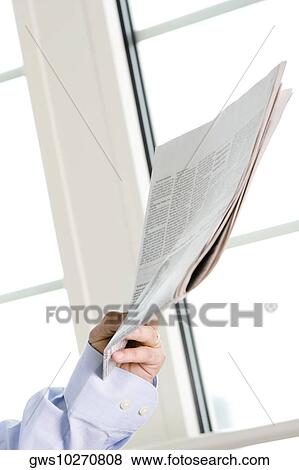 Stock Photo - Close-up of a person's hand holding a newspaper. Fotosearch