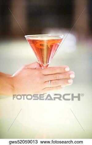 Close-up of a woman's hand holding a glass of martini View Large Photo Image Stock Image - Close-up of a woman's hand holding a glass of martini. Fotosearch