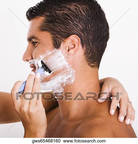 Stock Image - Close-up of a woman's hand shaving a mid adult man. Fotosearch