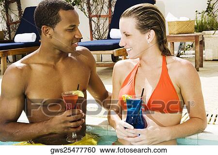 Stock Image - Close-up of a young couple looking at each other in a swimming pool. Fotosearch