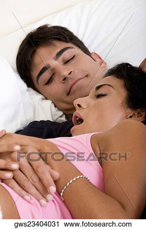 Stock Image - Close-up of a young couple lying on the bed. Fotosearch