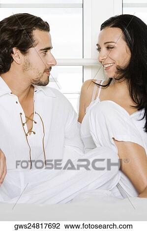Close-up of a young couple sitting on the bed and looking at each other View Large Photo Image Stock Image - Close-up of a young couple sitting on the bed and looking at each other. Fotosearch