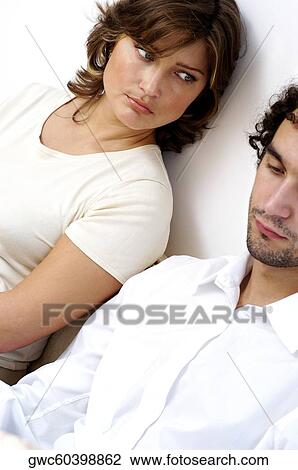 Stock Image - Close-up of a young couple sitting against a wall. Fotosearch