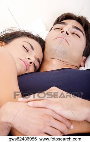 Close-up of a young couple sleeping on a bed View Large Photo Image Stock Photograph - Close-up of a young couple sleeping on a bed. Fotosearch