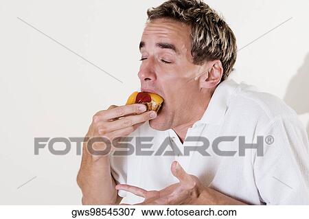 Close-up of a young man eating a strawberry tart View Large Photo Image Stock Photo - Close-up of a young man eating a strawberry tart. Fotosearch